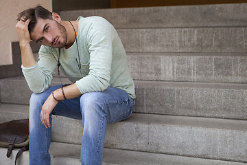 Image showing Casual  young man sitting on steps