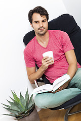 Image showing Man Sitting on Chair with Book and a Drink