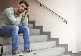 Image showing Casual  young man sitting on steps