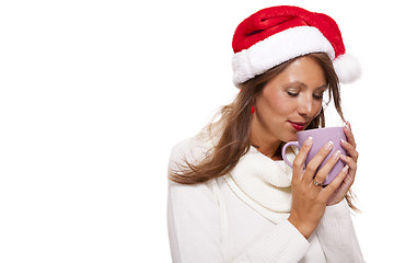 Image showing Cold young woman in a Santa hat sipping coffee tea