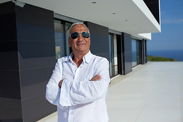 Image showing senior man in front of modern home