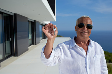 Image showing senior man in front of modern home