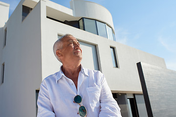 Image showing senior man in front of modern home