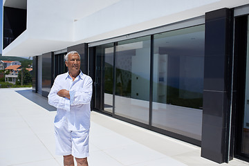 Image showing senior man in front of modern home