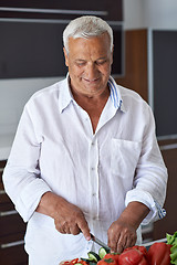 Image showing senior man cooking at home preparing salad in kitchen