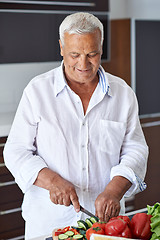 Image showing senior man cooking at home preparing salad in kitchen