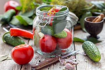 Image showing Vegetables and herbs in the glass jar on a wooden table.