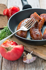 Image showing Fork and fried sausage in a skillet.