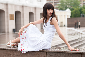 Image showing Attractive sad girl sits near city theater