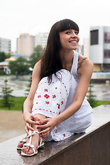 Image showing Attractive smiling woman sits over city background