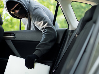 Image showing Car theft - a laptop being stolen through the window of an unoccupied car.