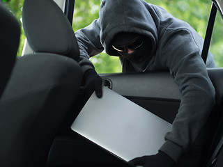 Image showing Car theft - a laptop being stolen through the window of an unoccupied car.