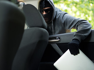 Image showing Car theft - a laptop being stolen through the window of an unoccupied car.