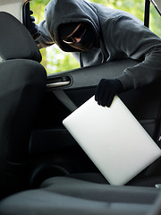 Image showing Car theft - a laptop being stolen through the window of an unoccupied car.