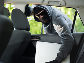 Image showing Car theft - a laptop being stolen through the window of an unoccupied car.