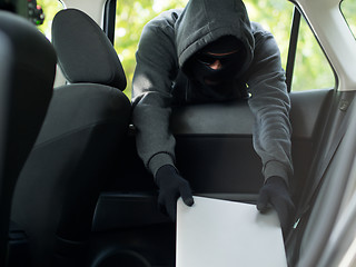 Image showing Car theft - a laptop being stolen through the window of an unoccupied car.