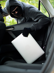 Image showing Car theft - a laptop being stolen through the window of an unoccupied car.