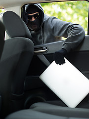 Image showing Car theft - a laptop being stolen through the window of an unoccupied car.