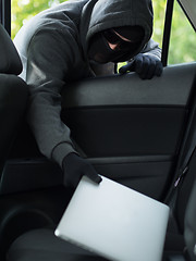 Image showing Car theft - a laptop being stolen through the window of an unoccupied car.