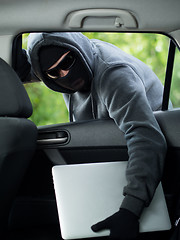 Image showing Car theft - a laptop being stolen through the window of an unoccupied car.