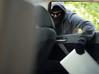 Image showing Car theft - a laptop being stolen through the window of an unoccupied car.