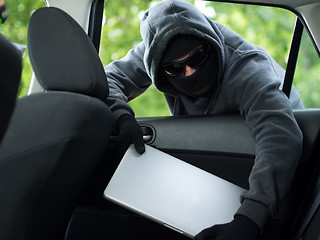 Image showing Car theft - a laptop being stolen through the window of an unoccupied car.