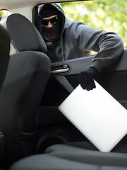 Image showing Car theft - a laptop being stolen through the window of an unoccupied car.