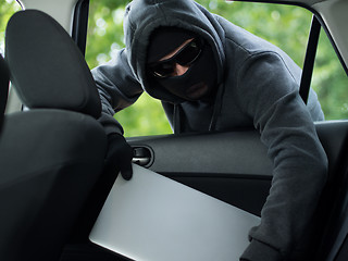 Image showing Car theft - a laptop being stolen through the window of an unoccupied car.