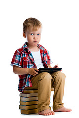 Image showing Little boy with a tablet computer sitting on the books