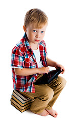 Image showing Little boy with a tablet computer sitting on the books