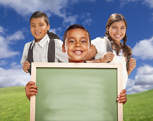 Image showing Hispanic Boys and Girl In Field Holding Blank Chalk Board