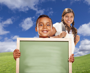 Image showing Hispanic Boy and Girl In Field Holding Blank Chalk Board