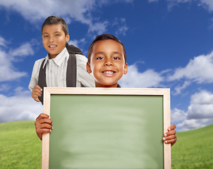 Image showing Happy Hispanic Boys In Grass Field Holding Blank Chalk Board