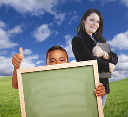 Image showing Young Boy with Blank Chalk Board, Teacher Behind on Grass