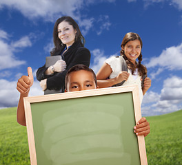 Image showing Young Students with Blank Chalk Board, Teacher Behind on Grass