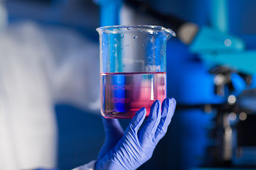 Image showing close up of hand holding glass in chemical lab