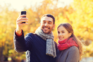 Image showing smiling couple with smartphone in autumn park