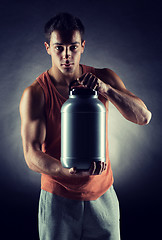 Image showing young male bodybuilder holding jar with protein