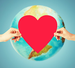 Image showing human hands holding red heart over earth globe