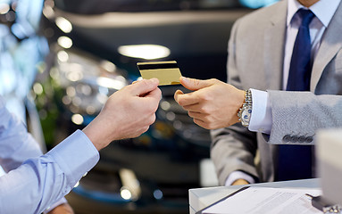 Image showing customer giving credit card to car dealer in salon