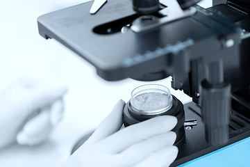 Image showing close up of hand with microscope and powder sample