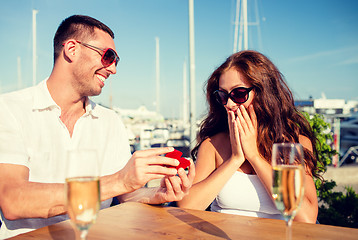 Image showing smiling couple with champagne and gift at cafe