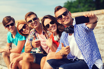 Image showing group of smiling friends with smartphone outdoors