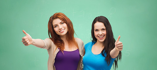 Image showing happy student girls showing thumbs up over green