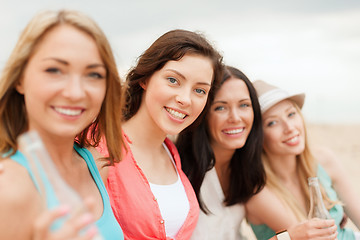 Image showing smiling girls with drinks on the beach