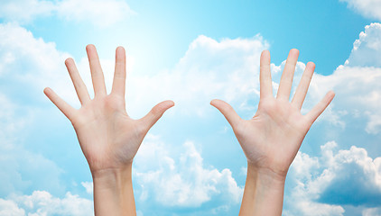 Image showing two woman hands making high five over blue sky