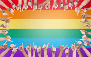 Image showing hands showing thumbs up in circle over rainbow