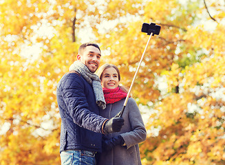 Image showing smiling couple with smartphone in autumn park