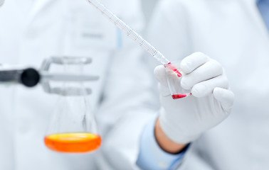 Image showing close up of scientists filling test tube in lab