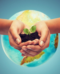 Image showing woman hand with green sprout over earth globe